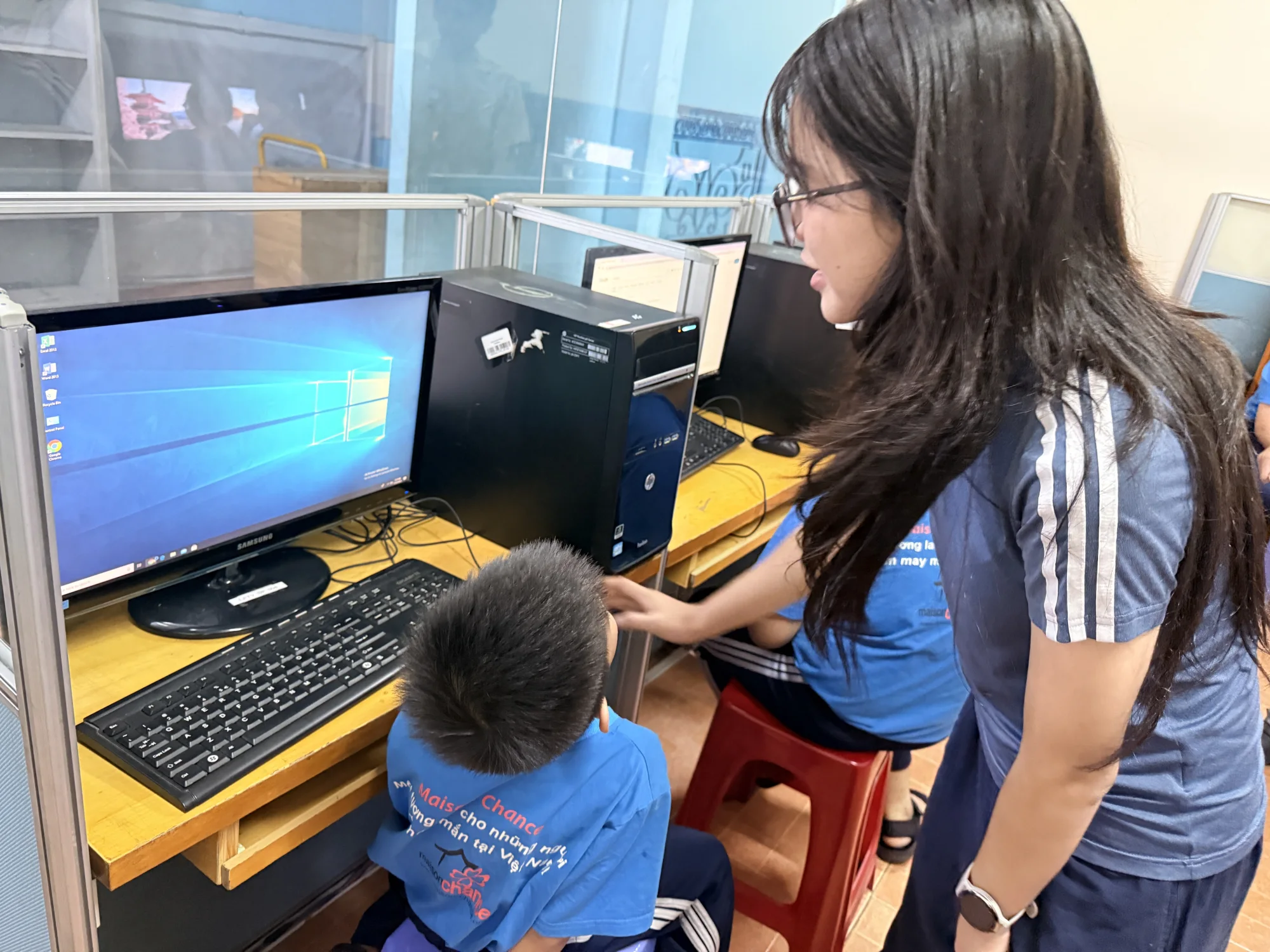 A student learning computer skills with guidance from Ngân